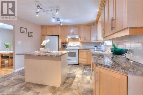 Kitchen featuring light brown cabinetry, a sink, under cabinet range hood, a center island, and white appliances - 105 Sabrina Crescent, Kitchener, ON - Indoor Photo Showing Kitchen