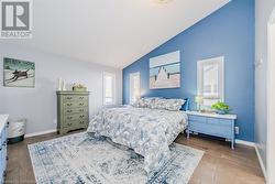 Primary bedroom featuring vaulted ceiling, light wood-style floors, and baseboards - 