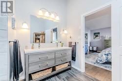 Bathroom featuring baseboards, double vanity, ensuite bathroom, wood finished floors, and a sink - 