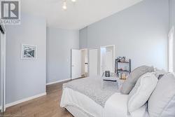 Bedroom with baseboards, high vaulted ceiling, and wood finished floors - 