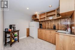 Kitchen with a sink, light colored carpet, recessed lighting, freestanding refrigerator, and open shelves - 