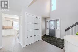 Foyer with light tile patterned floors, baseboards, a healthy amount of sunlight, and a towering ceiling - 