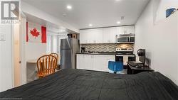 Kitchen featuring dark countertops, white cabinetry, stainless steel appliances, and backsplash - 