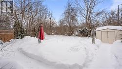 Yard covered in snow featuring an outbuilding, fence, and a storage shed - 