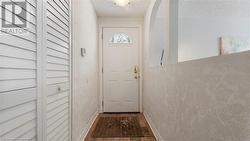 Doorway featuring baseboards, arched walkways, a textured ceiling, and wood finished floors - 