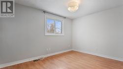 Unfurnished room featuring baseboards, a notable chandelier, a textured ceiling, and light wood finished floors - 