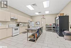 Kitchen with a paneled ceiling, under cabinet range hood, white appliances, visible vents, and light countertops - 