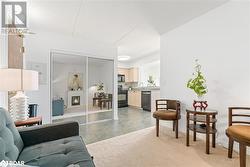 Living room with light carpet, a lit fireplace, light tile patterned floors, and baseboards - 