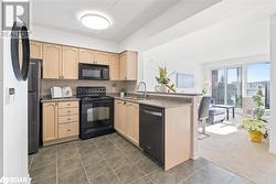 Kitchen with dark carpet, light brown cabinets, a sink, a peninsula, and black appliances - 