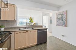 Kitchen featuring dishwasher, light brown cabinetry, backsplash, and a sink - 