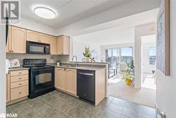 Kitchen featuring a sink, black appliances, a peninsula, and light brown cabinets - 