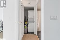 Clothes washing area featuring stacked washer and dryer, carpet flooring, laundry area, and tile patterned floors - 