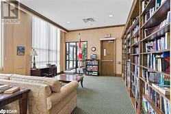 Living area with visible vents, ornamental molding, wall of books, carpet floors, and recessed lighting - 