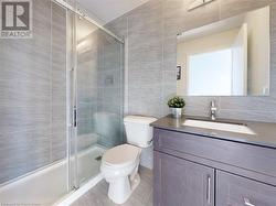 Bathroom with toilet, a tile shower, tile walls, and vanity - 