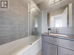 Bathroom with shower / bath combination with glass door, tile walls, and vanity - 