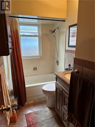 Full bath with vanity, tile patterned floors, toilet, shower / bath combo with shower curtain, and tile walls - 627 Upper Sherman Avenue, Hamilton, ON - Indoor Photo Showing Bathroom