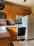 Kitchen featuring light tile patterned floors, brown cabinetry, fridge, range, and extractor fan - 627 Upper Sherman Avenue, Hamilton, ON  - Indoor Photo Showing Kitchen 