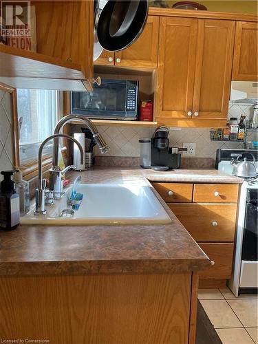 Kitchen featuring light tile patterned floors, a sink, brown cabinetry, decorative backsplash, and range - 627 Upper Sherman Avenue, Hamilton, ON - Indoor Photo Showing Kitchen