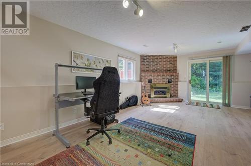 Office space with wood finished floors, baseboards, visible vents, a textured ceiling, and a brick fireplace - 431 Northlake Drive, Waterloo, ON - Indoor With Fireplace