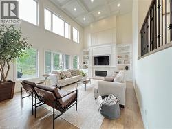 Living room featuring a high ceiling, light wood-style flooring, coffered ceiling, healthy amount of natural light, and recessed lighting - 
