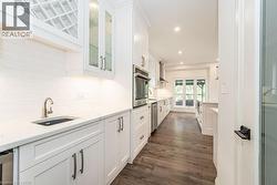 Kitchen with a sink, appliances with stainless steel finishes, white cabinets, tasteful backsplash, and glass insert cabinets - 