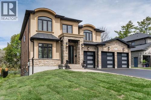 View of front of house featuring stone siding, a front lawn, stucco siding, driveway, and a standing seam roof - 346 Lexington Road, Waterloo, ON - Outdoor With Facade