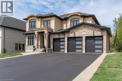 View of front of house featuring stucco siding, stone siding, and asphalt driveway - 