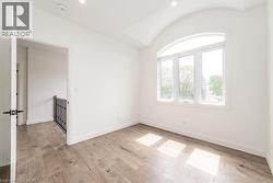 Empty room with a smoke detector, light wood-style floors, baseboards, and vaulted ceiling - 