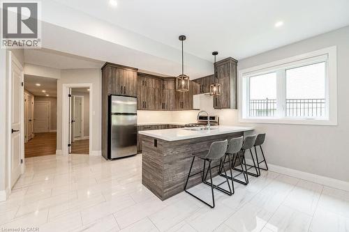 Kitchen featuring freestanding refrigerator, baseboards, a sink, a kitchen bar, and light countertops - 346 Lexington Road, Waterloo, ON - Indoor Photo Showing Kitchen