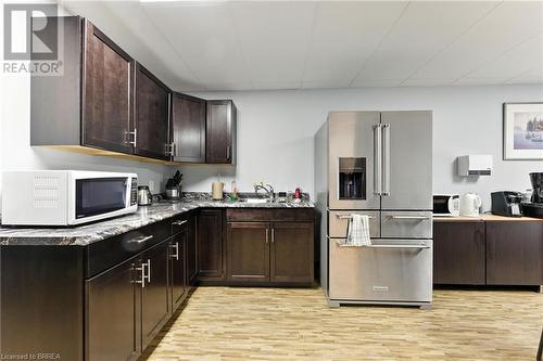 Kitchen with high end refrigerator, white microwave, light wood-style floors, and dark brown cabinetry - 207 Greenwich Street, Brantford, ON 