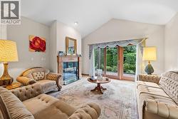 Formal living room with vaulted ceilings, bright windows, gas fireplace and patio access - 