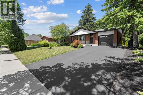 View of front of home with an attached garage, brick siding, asphalt driveway, and a front lawn - 79 Inwood Crescent, Kitchener, ON - Outdoor