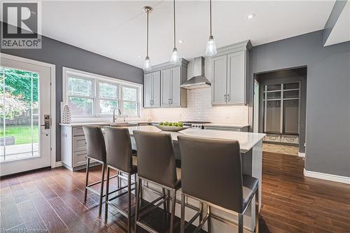 Kitchen featuring gray cabinets, wall chimney exhaust hood, light countertops, decorative backsplash, and dark wood-style floors - 25 Orchard Hill, Hamilton, ON - Indoor Photo Showing Kitchen With Upgraded Kitchen