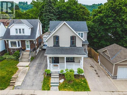 View of front of home featuring covered porch, brick siding, and a shingled roof - 25 Orchard Hill, Hamilton, ON - Outdoor With Deck Patio Veranda With Facade