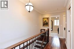 Hall with an upstairs landing, ornamental molding, and dark wood-style floors - 