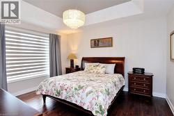 Bedroom with a raised ceiling, dark wood-type flooring, and a chandelier - 