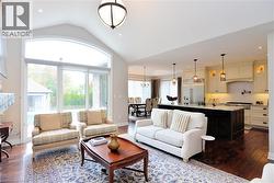 Living area with dark wood-style floors, vaulted ceiling, recessed lighting, and a chandelier - 