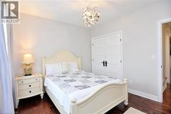 Bedroom featuring dark wood-type flooring, a chandelier, and a closet - 