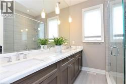 Full bathroom featuring double vanity, a stall shower, and plenty of natural light - 