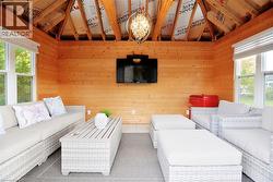 Living room featuring healthy amount of natural light, vaulted ceiling, and wood walls - 