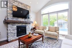 Living room featuring wood finished floors, vaulted ceiling, a fireplace, and recessed lighting - 
