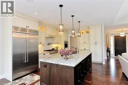 Kitchen featuring glass insert cabinets, stainless steel appliances, tasteful backsplash, light stone countertops, and recessed lighting - 