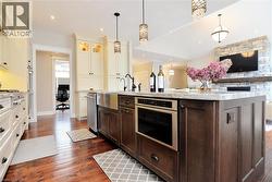 Kitchen featuring a desk, dark brown cabinets, open floor plan, pendant lighting, and glass insert cabinets - 