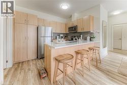 Kitchen with light brown cabinets, light wood-style flooring, appliances with stainless steel finishes, and a peninsula - 