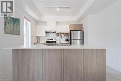 Kitchen featuring light wood-style flooring, modern cabinets, a center island with sink, appliances with stainless steel finishes, and tasteful backsplash - 