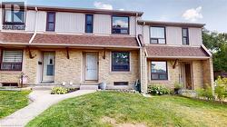 View of front facade featuring a front yard, stone siding, covered porch, and roof with shingles - 