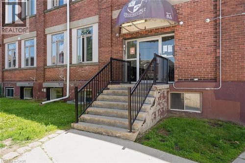 View of exterior entry with brick siding and a lawn - 27 Bridge Street Unit# 107, Brantford, ON - Outdoor