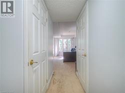 Corridor featuring light colored carpet and a textured ceiling - 