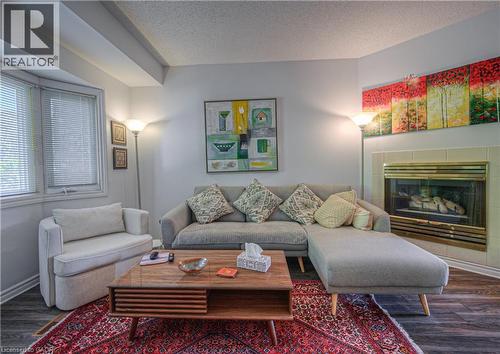 Living room featuring wood finished floors, a textured ceiling, and a tiled fireplace - 310 Christopher Drive Unit# 15, Cambridge, ON - Indoor Photo Showing Living Room With Fireplace