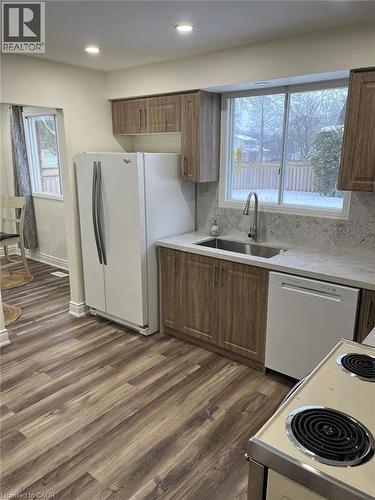 Kitchen featuring white appliances, brown cabinets, dark wood finished floors, backsplash, and recessed lighting - 389 Dunvegan Drive, Waterloo, ON - Indoor Photo Showing Kitchen With Double Sink